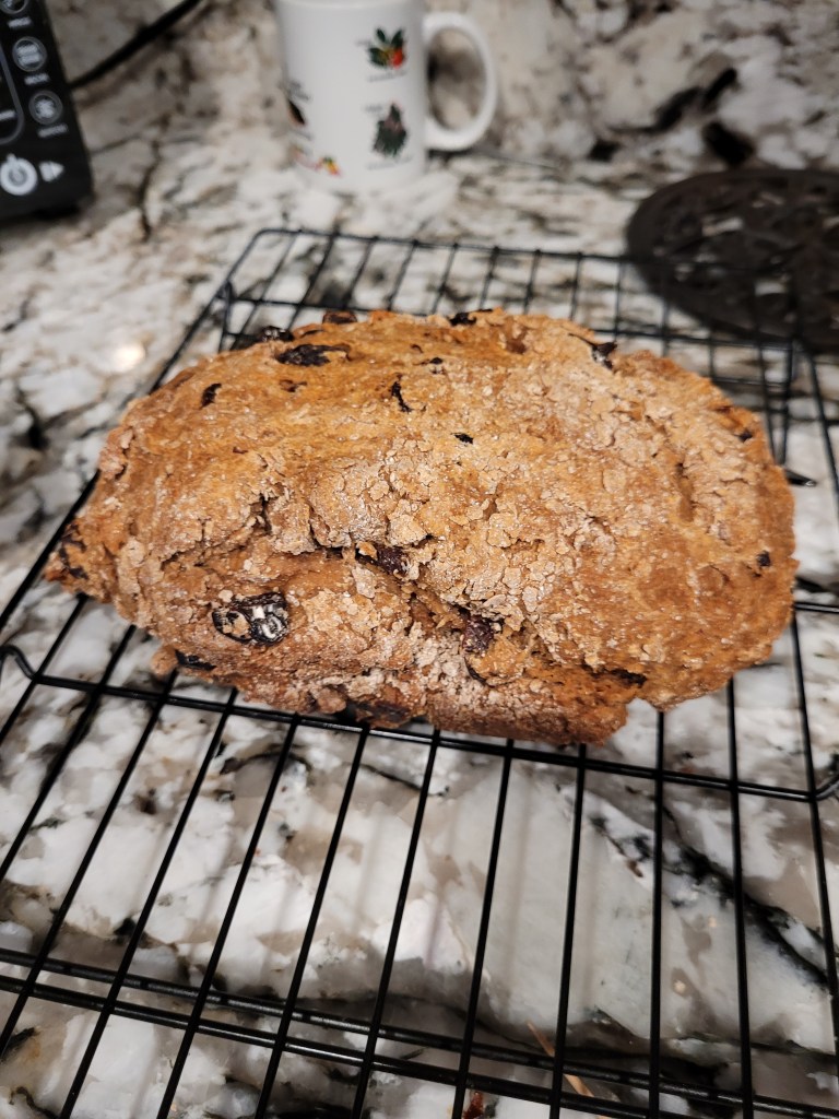 image of home-baked soda bread warm from the oven.  Golden brown with raisins and cherries peeking from the top.
